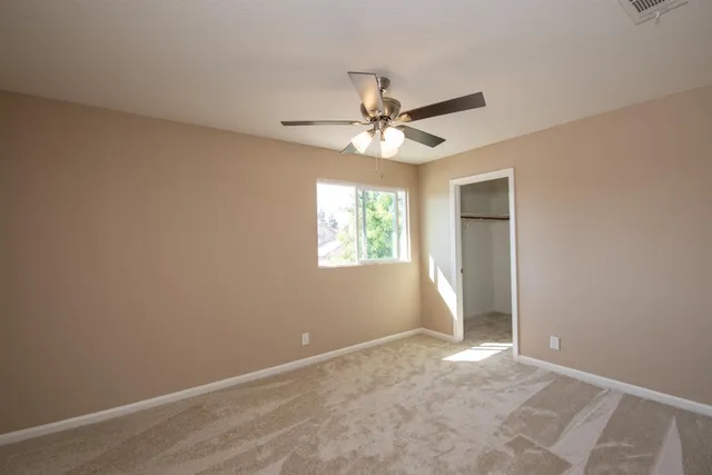 an empty room with a window and a fan