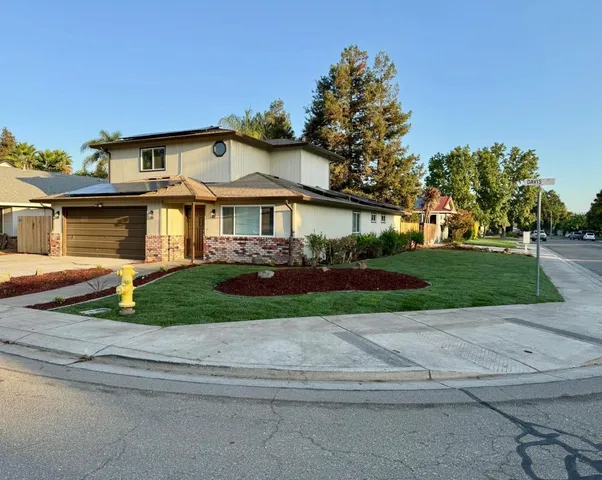 a front view of a house with a yard and potted plants