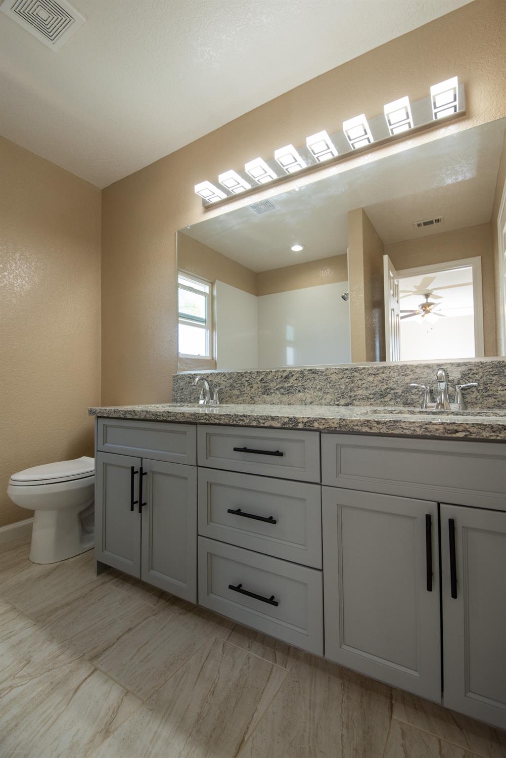 1621 Davis Street Ripon, CA 95366 - Photo 36 of 43 a bathroom with a granite countertop sink a toilet and a mirror