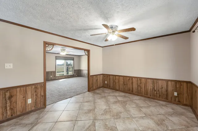 a view of an empty room with chandelier fan and wooden floor