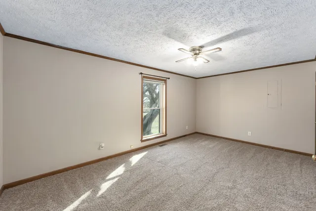 an empty room with a ceiling fan and a window