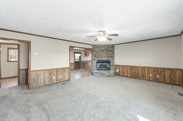 an empty room with chandelier fan and fireplace