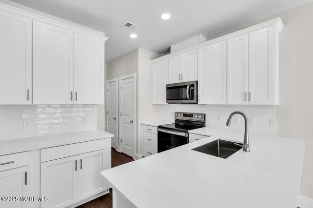 a kitchen with stainless steel appliances granite countertop a sink a stove a refrigerator and cabinets