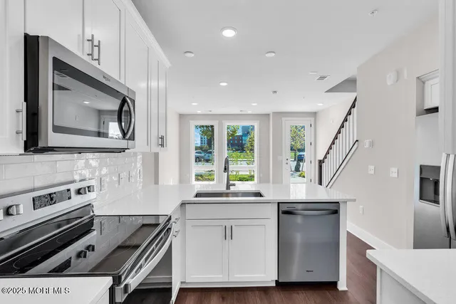 a kitchen with kitchen island granite countertop a stove a sink and a microwave