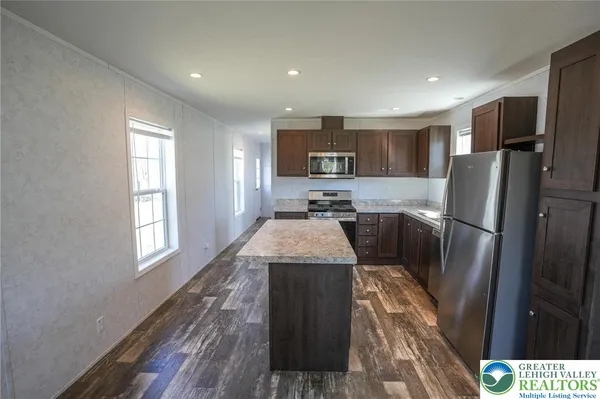 a kitchen with stainless steel appliances granite countertop a refrigerator a stove a sink a microwave and island