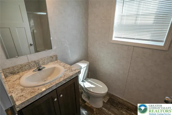 a bathroom with a granite countertop toilet a sink and a window