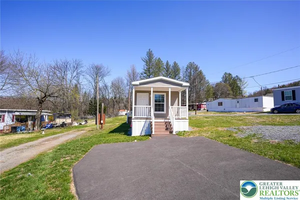 a front view of house with yard and trees in the background