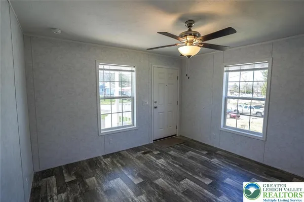 a view of an empty room with window and chandelier fan