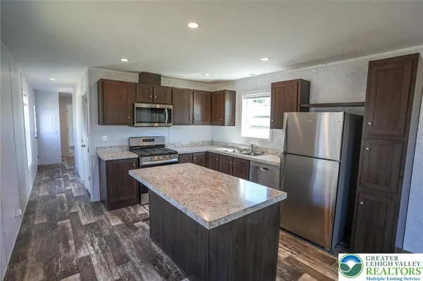 a kitchen with stainless steel appliances granite countertop a refrigerator a stove a sink a microwave and a refrigerator