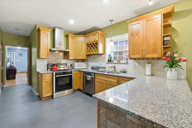 a kitchen with stainless steel appliances granite countertop a sink a stove and a refrigerator