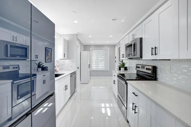 a large kitchen with stainless steel appliances granite countertop a stove a sink dishwasher and a microwave oven with white cabinets