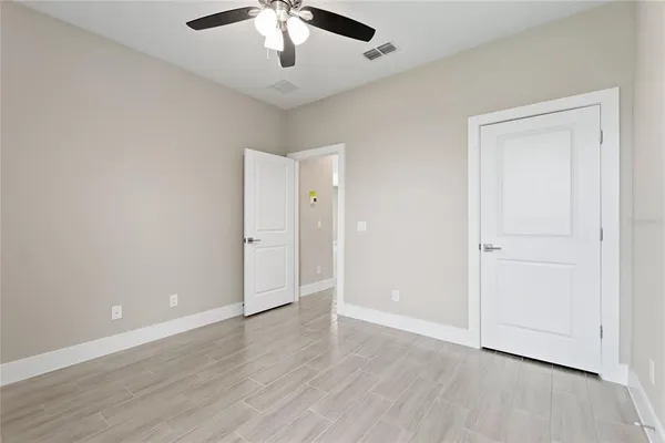 an empty room with wooden floor fan and windows