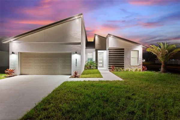 a view of yellow house with a yard and potted plants