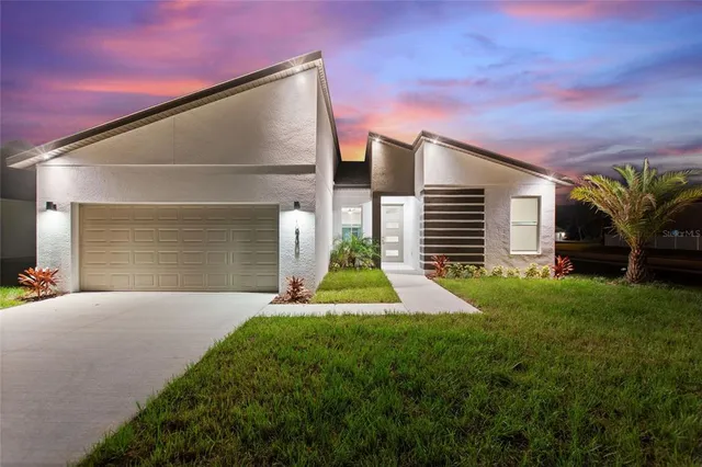 a view of yellow house with a yard and potted plants