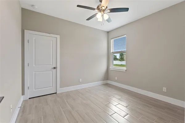 an empty room with wooden floor and ceiling fan