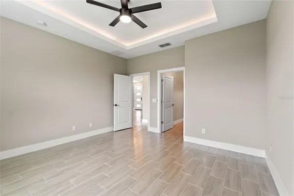 an empty room with wooden floor windows and fan
