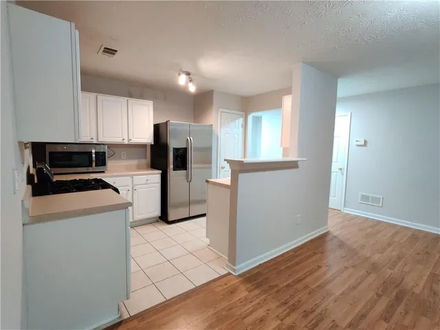a kitchen with a refrigerator a stove top oven and cabinets