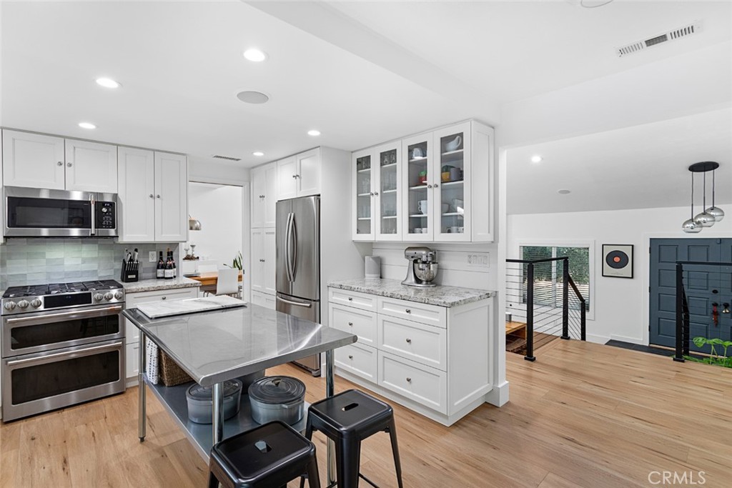 5555 Fairview Place Agoura Hills, CA 91301 - Photo 10 of 39 a kitchen with stainless steel appliances a stove a sink dishwasher a refrigerator white cabinets and wooden floor