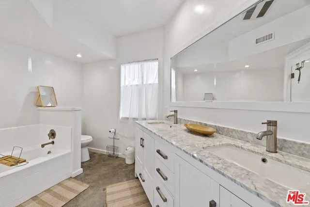 a bathroom with a granite countertop tub and 2 sink