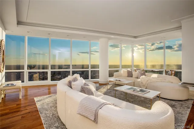 a living room with furniture large windows and wooden floor