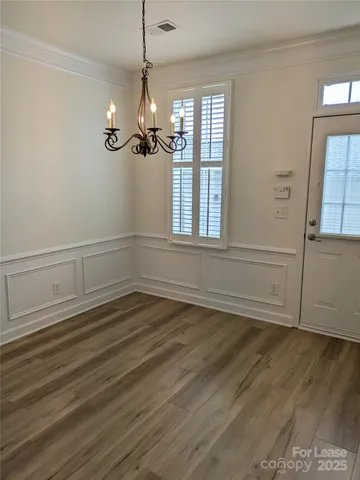 an empty room with wooden floor cabinet and windows