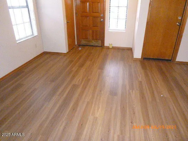 an empty room with wooden floor and windows