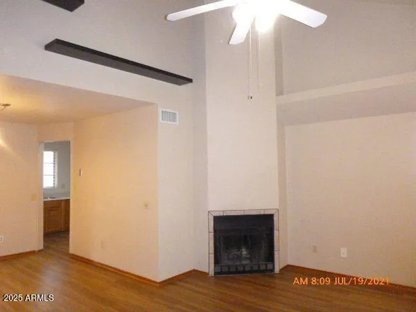 a view of an empty room with wooden floor and a fireplace