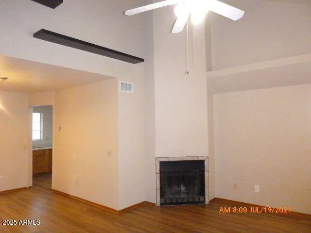 a view of an empty room with wooden floor and a fireplace