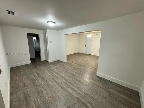 a view of an empty room with closet and wooden floor
