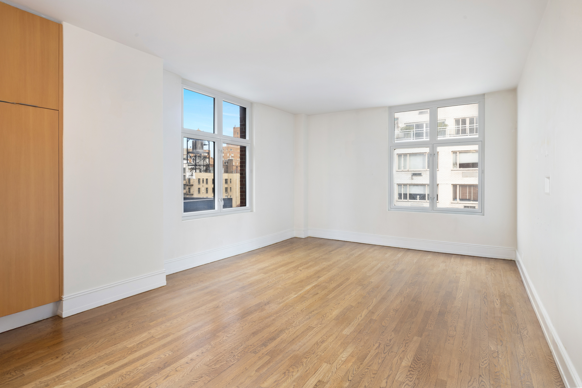 188 East 70th Street, Unit 11D Manhattan, NY 10021 - Photo 2 of 14 an empty room with wooden floor and windows