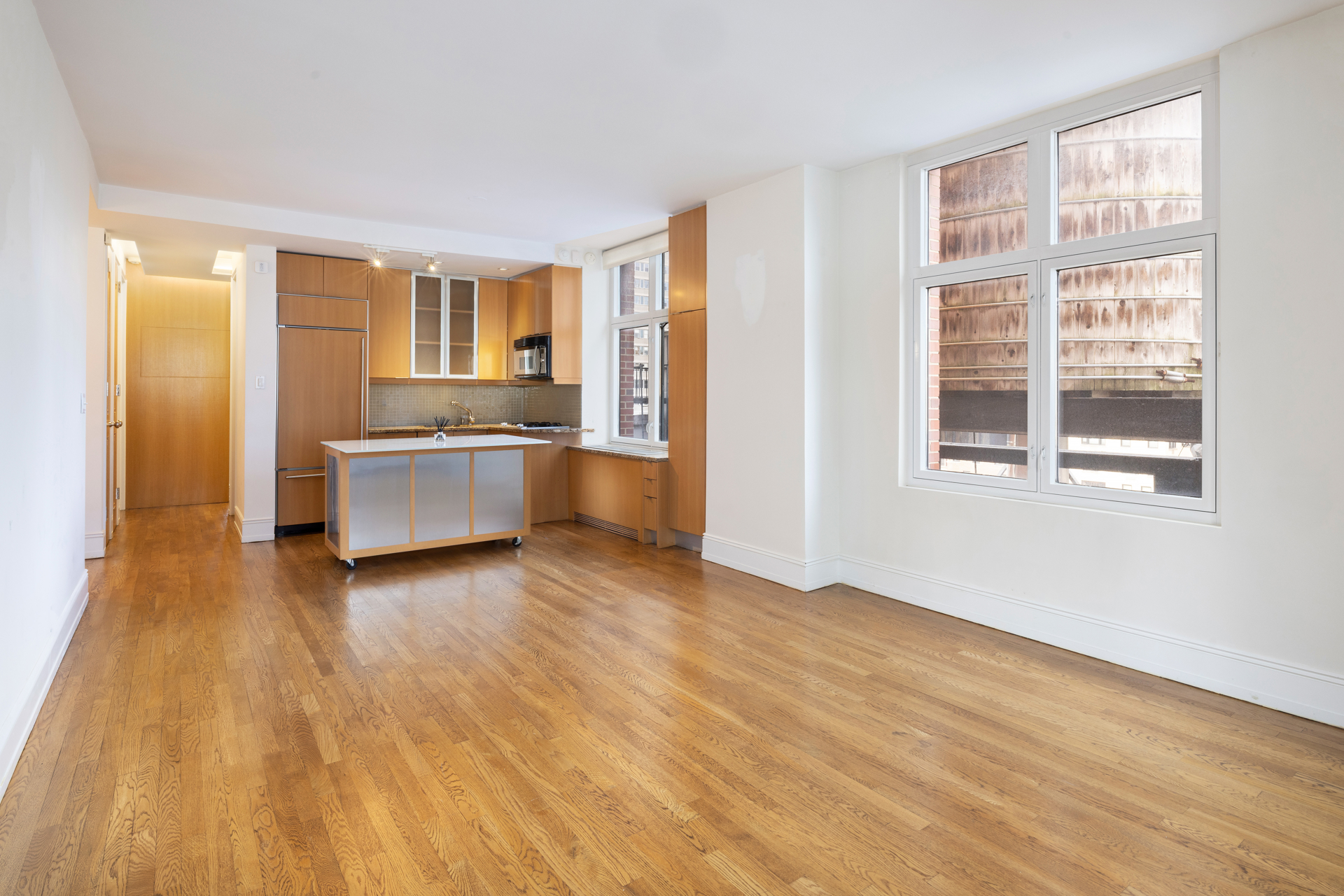 188 East 70th Street, Unit 11D Manhattan, NY 10021 - Photo 3 of 14 a view of an empty room with a kitchen and wooden floor