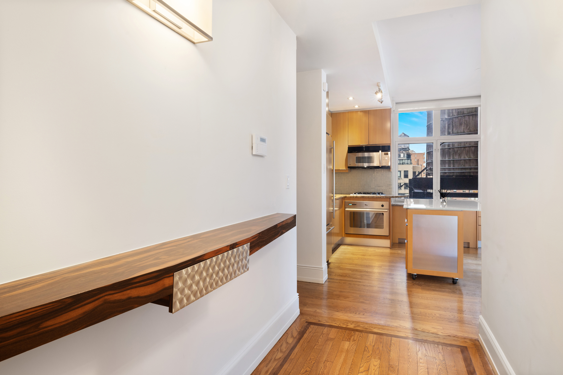 188 East 70th Street, Unit 11D Manhattan, NY 10021 - Photo 8 of 14 a view of living room with kitchen island stainless steel appliances wooden floor and window