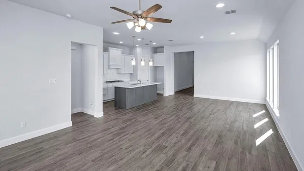 a view of a big room with wooden floor and kitchen