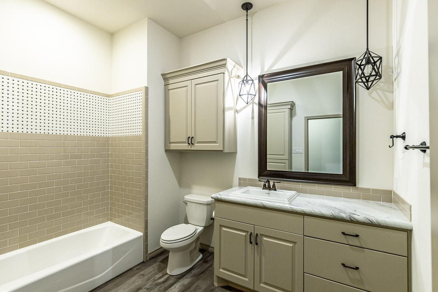 3633 133rd Street Lubbock, TX 79423 - Photo 33 of 46 a bathroom with a granite countertop sink a toilet and shower