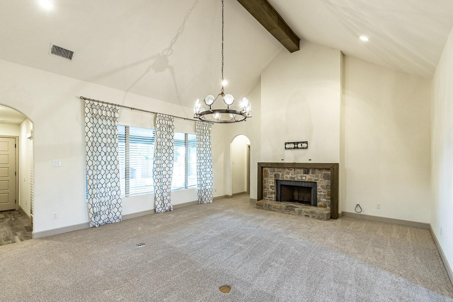 3633 133rd Street Lubbock, TX 79423 - Photo 7 of 46 an empty room with fireplace chandelier and windows