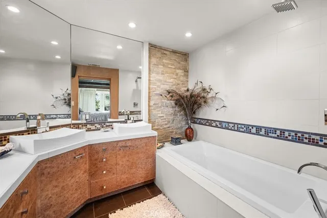 a bathroom with a bathtub a mirror a sink and vanity