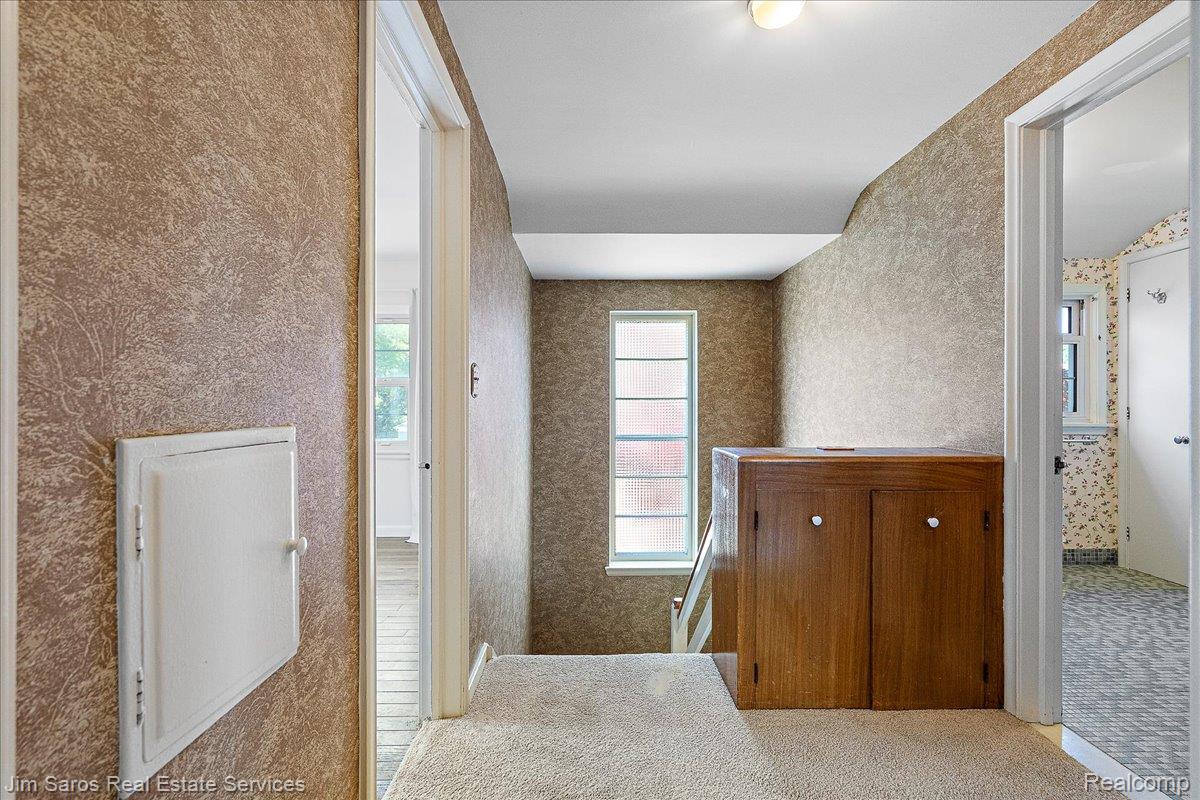 1010 Nottingham Road Grosse Pointe, MI 48230 - Photo 17 of 30 Upper-level hallway with textured wallpaper, neutral carpeting, and a built-in wood-finish cabinet