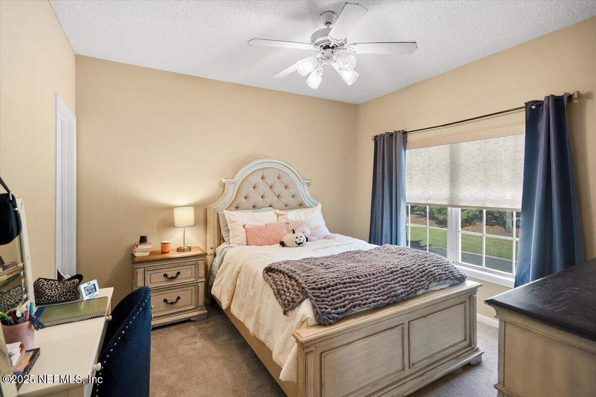 2493 Tall Cedars Road Fleming Island, FL 32003 - Photo 31 of 68 a bedroom with a bed a chandelier and a window