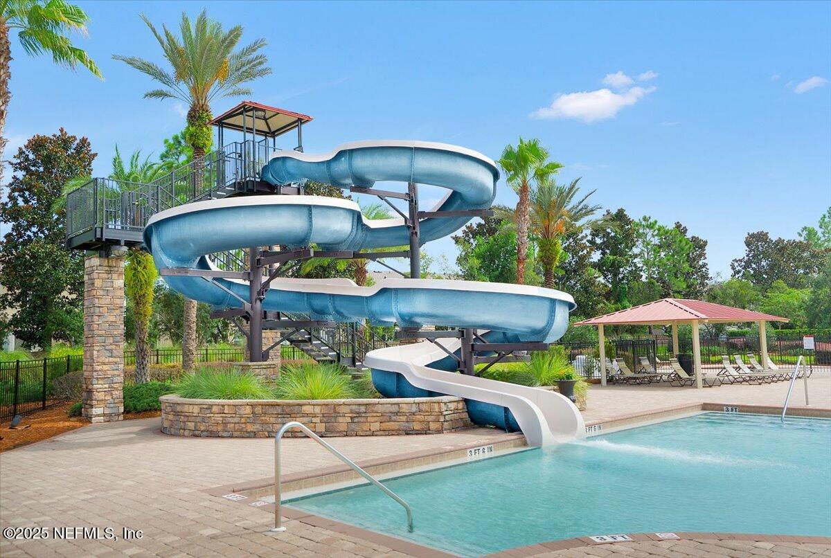 2493 Tall Cedars Road Fleming Island, FL 32003 - Photo 50 of 68 a view of a patio with couches table and chairs under an umbrella with a fire pit