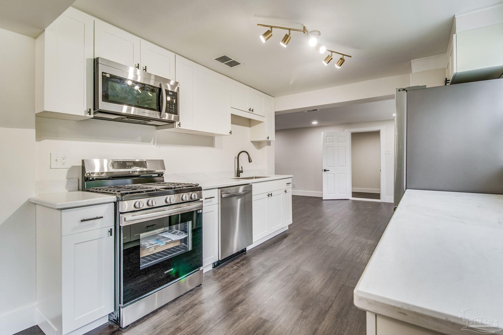 4355 Highway 95A North Molino, FL 32577 - Photo 17 of 54 a kitchen with stainless steel appliances granite countertop a stove top oven a sink dishwasher and white cabinets with wooden floor