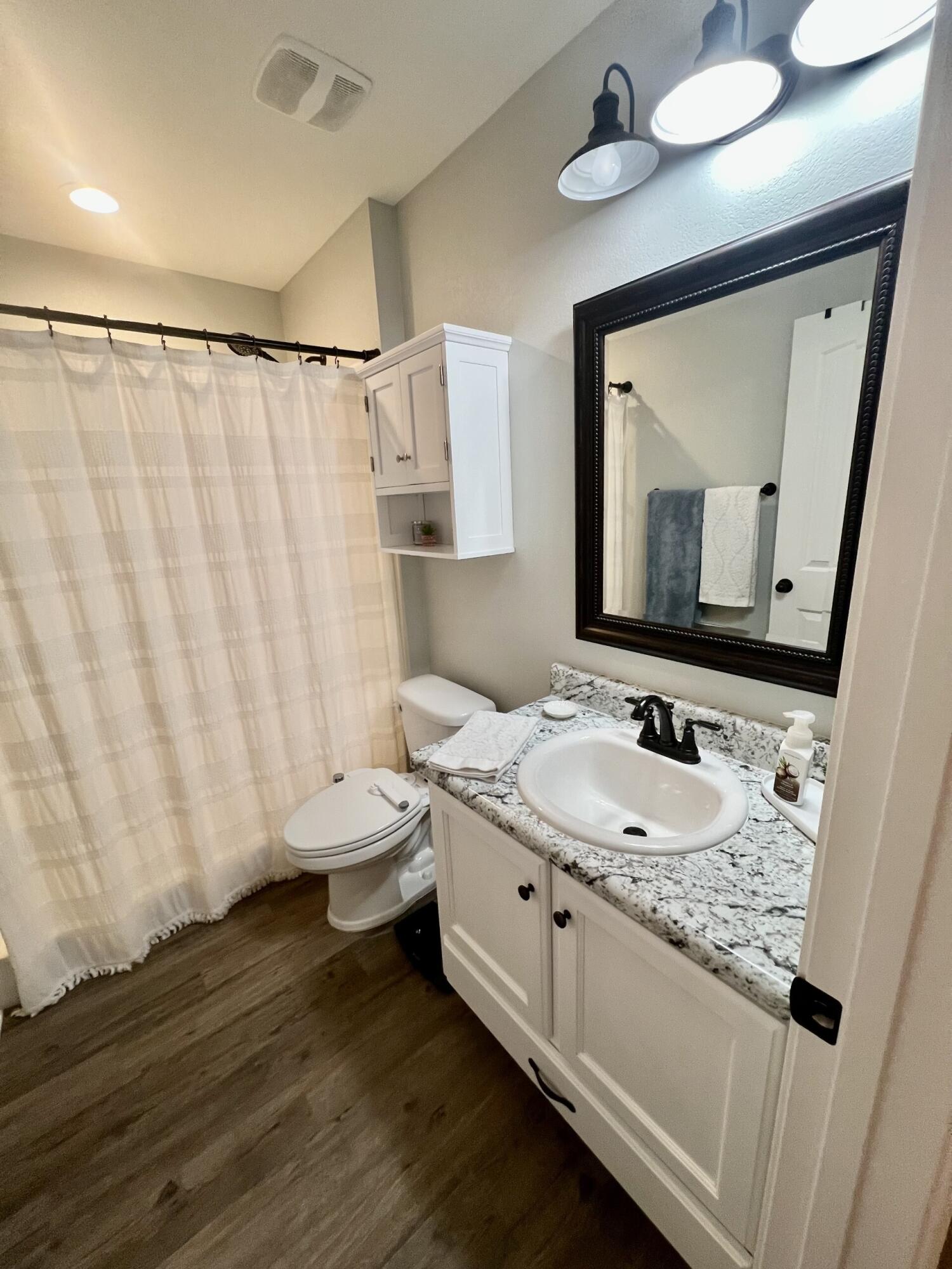 4948 Guernsey Road Pace, FL 32571 - Photo 18 of 25 a bathroom with a granite countertop sink a toilet and a mirror