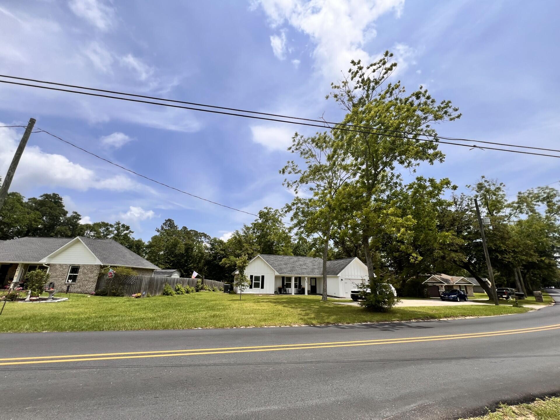 4948 Guernsey Road Pace, FL 32571 - Photo 3 of 25 a front view of a house with a garden and trees