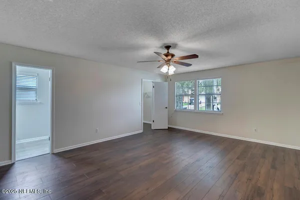 a view of an empty room with a window and wooden floor
