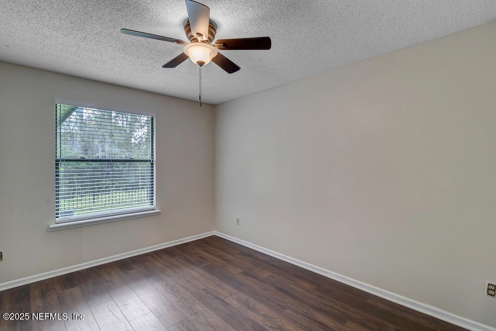 4518 Crosstie Road South Jacksonville, FL 32257 - Photo 23 of 28 an empty room with wooden floor chandelier fan and windows