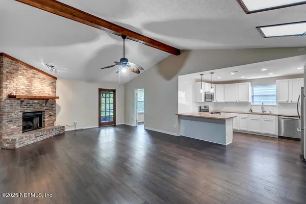 a large kitchen with cabinets wooden floor a fireplace and a window