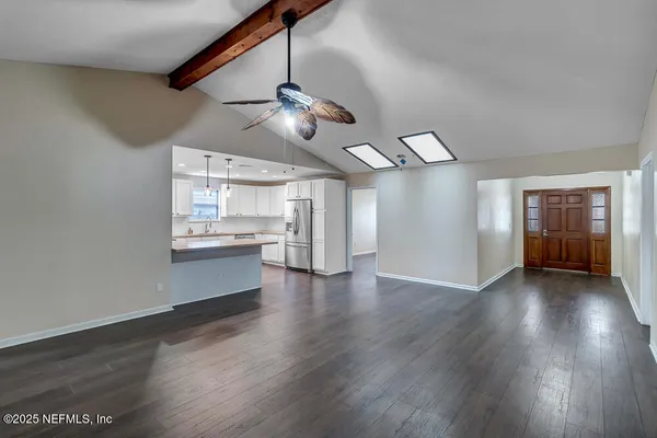 a view of an empty room with window wooden floor and a kitchen