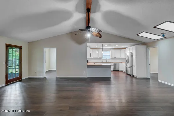 a view of a kitchen with wooden floor a sink a refrigerator and window