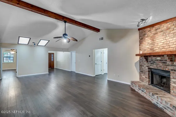 a view of an empty room with wooden floor fireplace and a window