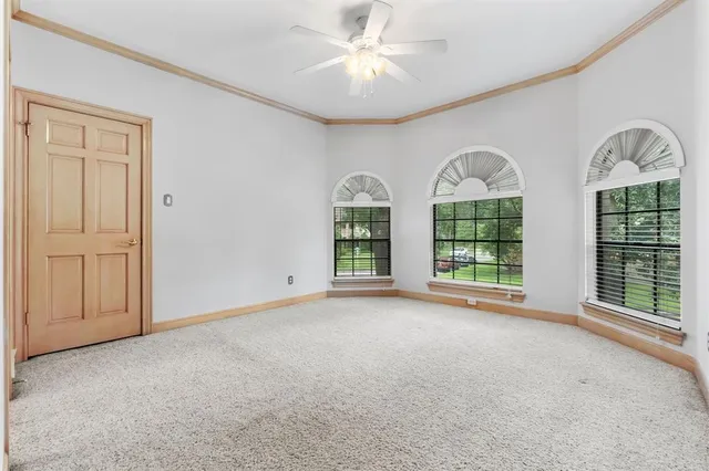 a view of an empty room with window and chandelier fan