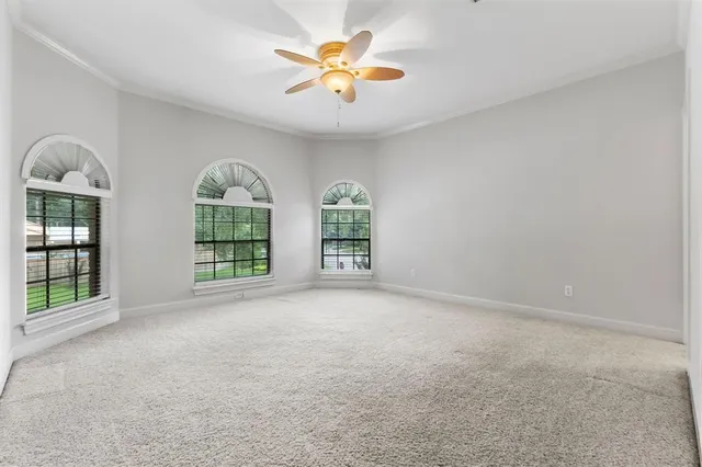 an empty room with windows and ceiling fan